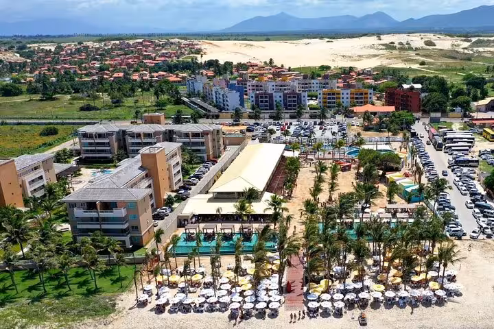 Aerial view of Cumbuco Beach resort and beachfront umbrellas with sand dunes behind, Ceará day tour stop