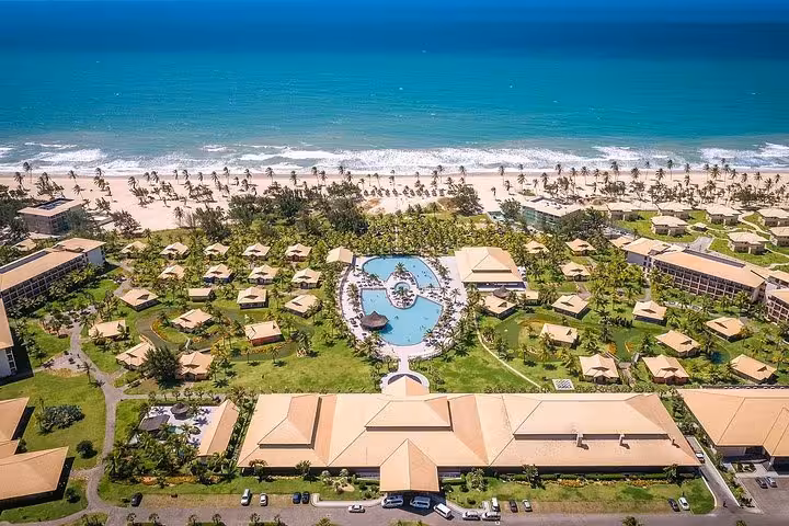 Drone view of beachfront resort pools and palm-lined shore at Cumbuco Beach, Ceará Brazil coastal day trip