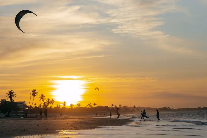 Sunset at Cumbuco Beach with kitesurfers and palm-lined shoreline, perfect for a Cumbuco Beach Tour