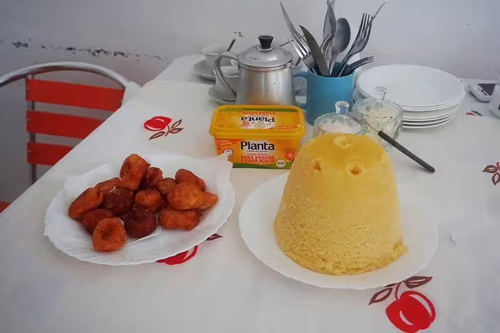 Cuscuz and fried snacks on a table with butter, depicting a traditional meal experience at the Banana Plantation tour.