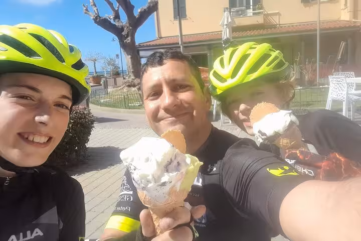 Cyclists in bright helmets enjoying gelato during a sunny break on the Riviera dei Fiori bike tour in Sanremo.