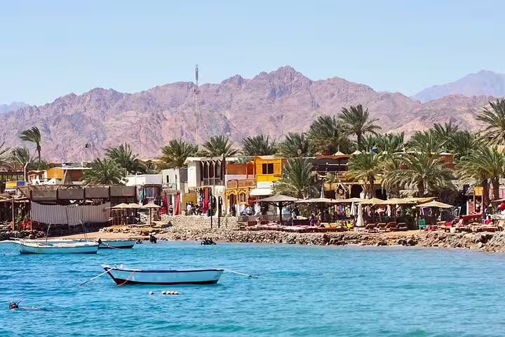 Dahab waterfront with boats and palm-lined cafes, Red Sea stop on Sharm El Sheikh to Dahab snorkeling day trip