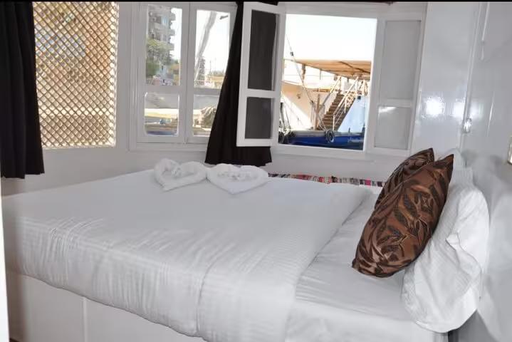Bright dahabiya cabin double bed with open window view, ideal for 5 days 4 nights Nile cruise Egypt