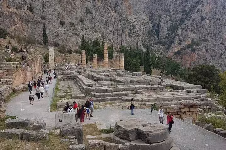 Ancient Delphi archaeological site with temple ruins and visitors, part of Delphi and Meteora 2-day tour