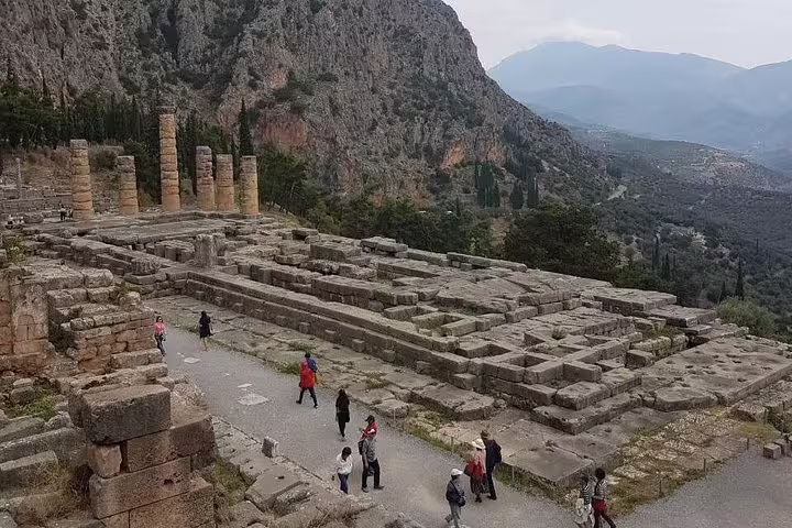Visitors exploring Delphi archaeological site ruins and columns, stop on Delphi and Meteora 2-day private tour