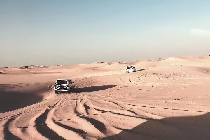Off-road vehicles navigating expansive desert dunes, highlighting an exciting dune bashing experience.