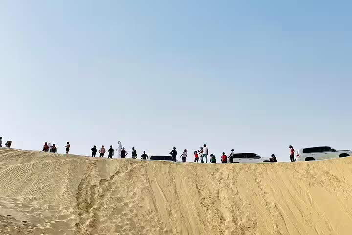 Tourists gather atop a golden sand dune, ready for an adventurous desert safari experience.
