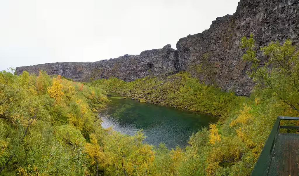 Emerald green lake nestled in a lava canyon surrounded by autumn trees near Akureyri Iceland