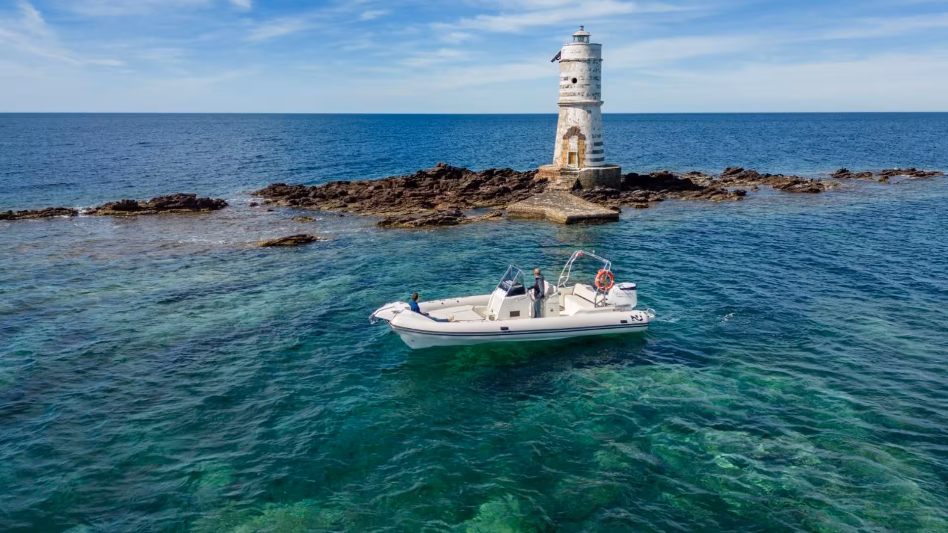 Dinghy near a historic lighthouse on rocky islet between Carloforte and Sant'Antioco during a 4-hour tour.