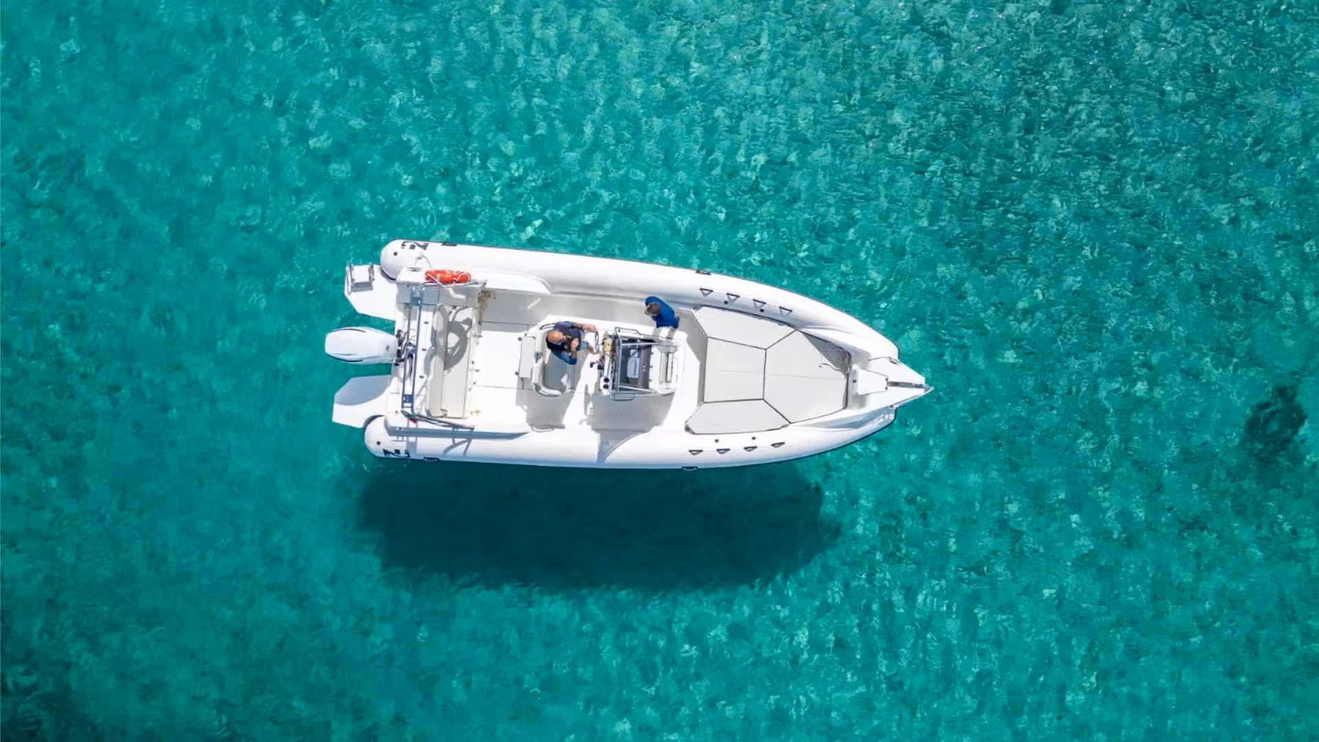 Aerial view of a white dinghy floating on crystal-clear waters near Sant'Antioco, perfect for scenic tours.