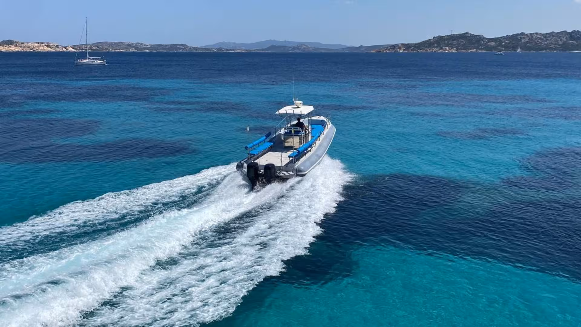 Dinghy cruising through turquoise waters near Santa Teresa di Gallura with stunning Corsican coastline views.