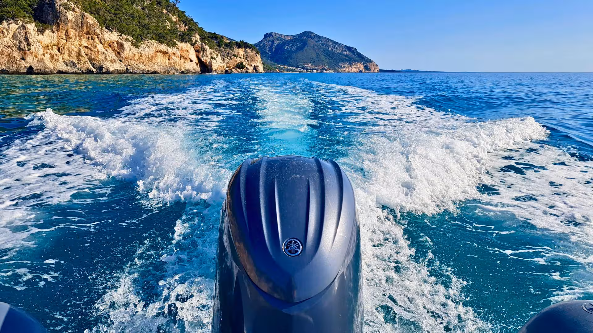 View from a dinghy gliding through the Gulf of Orosei, showcasing stunning coastal cliffs and clear blue waters.