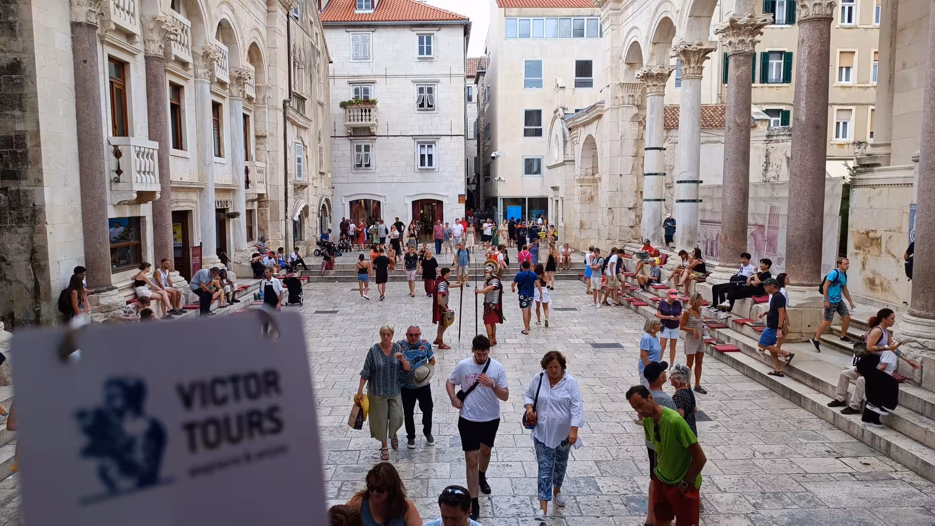 Tourists explore the historic architecture of Diocletian's Palace in Split, Croatia, on a sunny day.