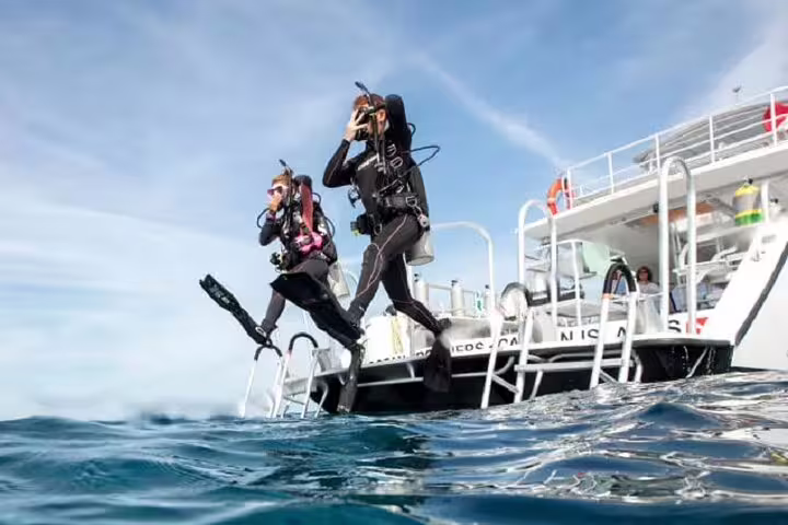 Divers giant-stride from a VIP boat in Sharm El Sheikh for Ras Mohamed and White Island snorkeling trip
