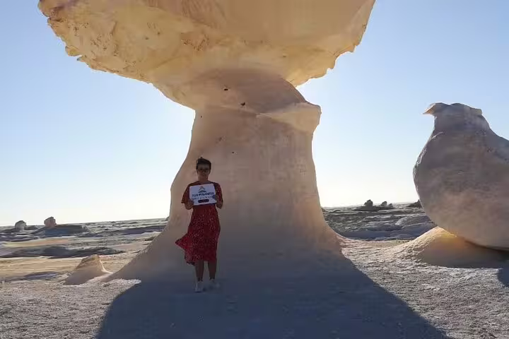 Traveler under White Desert mushroom rock in Egypt, featured on 5-day Djara Cave and Black & White Desert camping tour