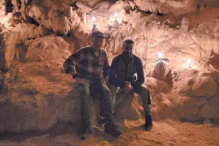 Travelers inside Djara Cave, Egypt, exploring candlelit limestone chambers on 3-day White Desert tour