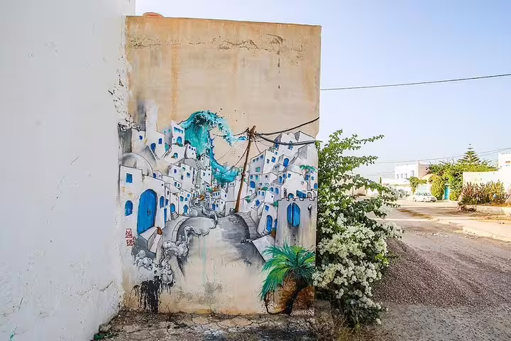 Vibrant street art depicting traditional Tunisian architecture adorns a wall in Djerbahood, Tunisia.