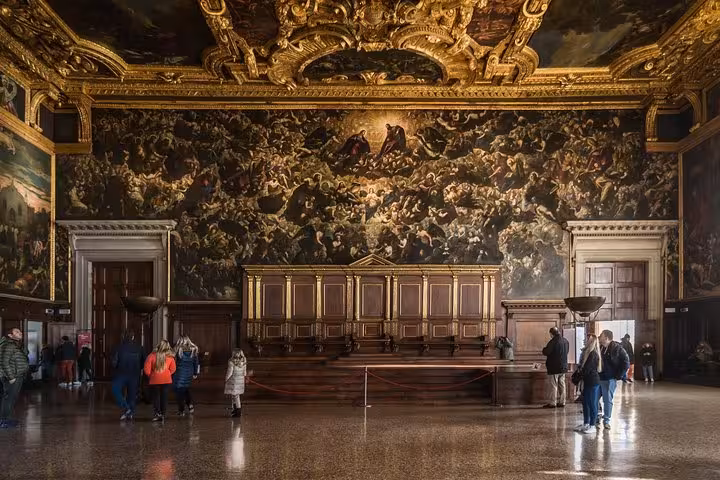 Visitors admire the grand Hall of the Great Council in Doge's Palace, Venice, with its ornate frescoes and gilded ceiling.
