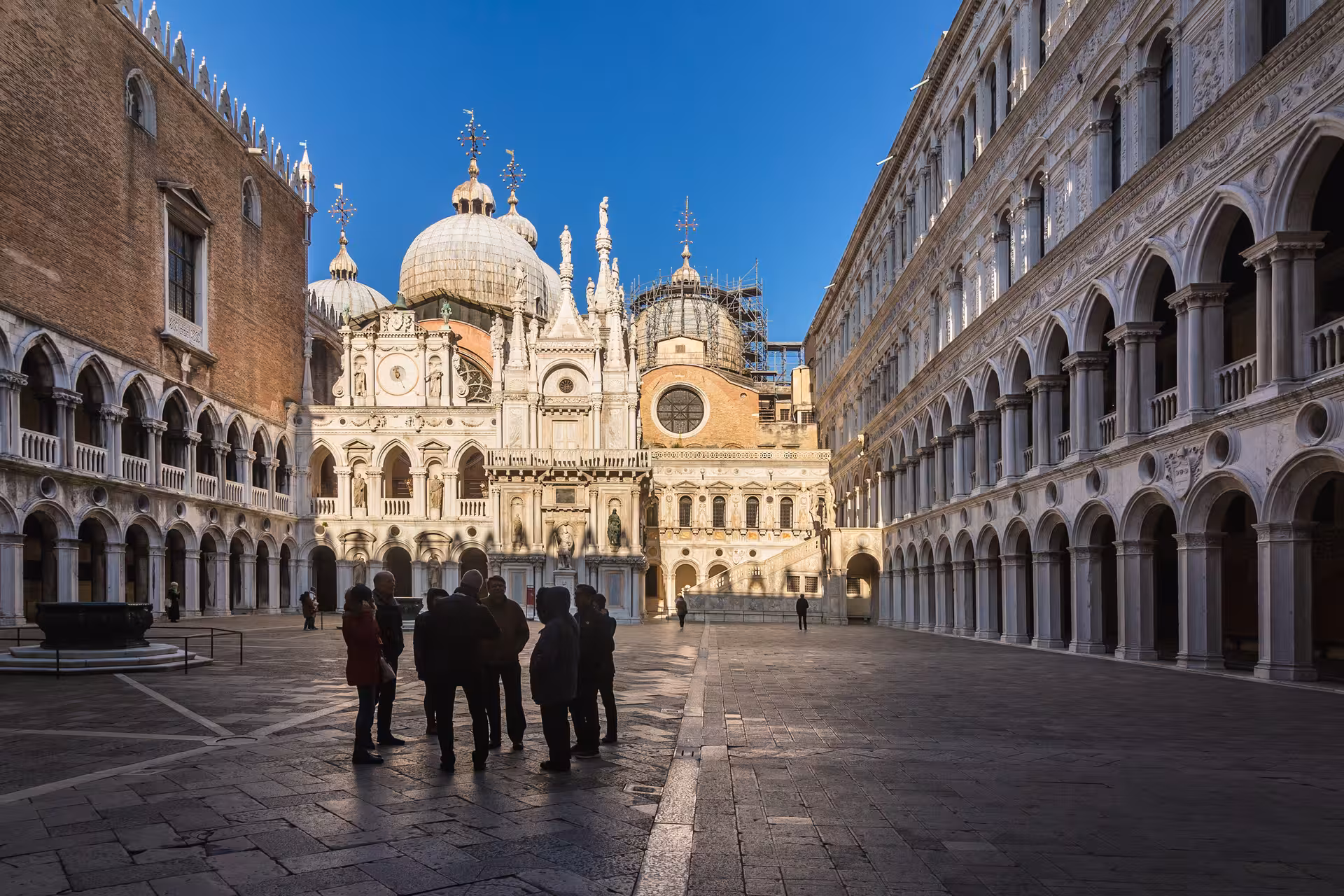 Visitors explore the ornate courtyard of Doge's Palace, surrounded by intricate Venetian architecture.