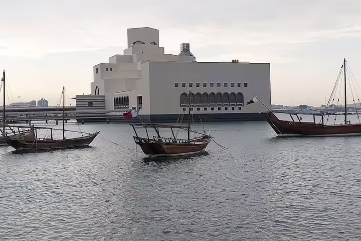 Traditional dhow boats float near the iconic Museum of Islamic Art in Doha, offering a glimpse of Qatar's cultural heritage.
