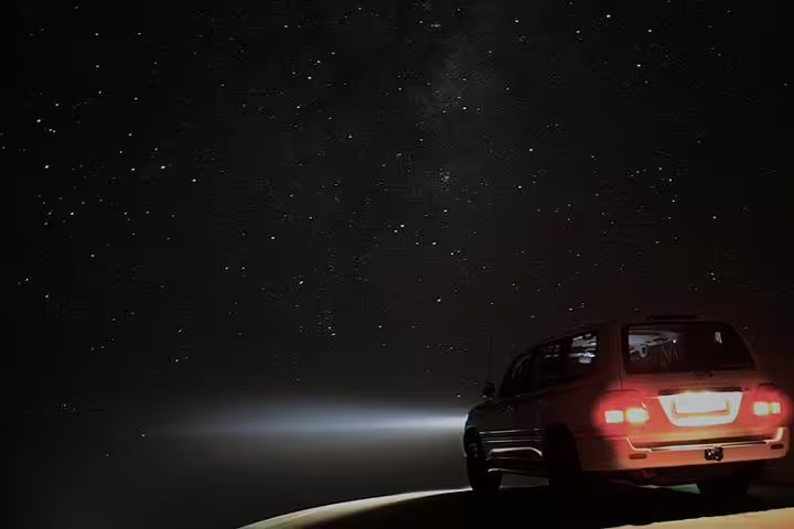 SUV on a sand dune under a starlit sky, perfect for Doha night desert safari and dune bashing adventure.
