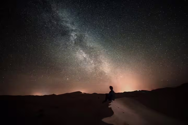 Person gazing at the Milky Way in Doha's desert, highlighting the allure of night safari tours.