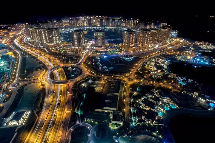 Aerial view of Doha's illuminated skyline and bustling streets at night, showcasing the city's modern architecture and vibrant nightlife.