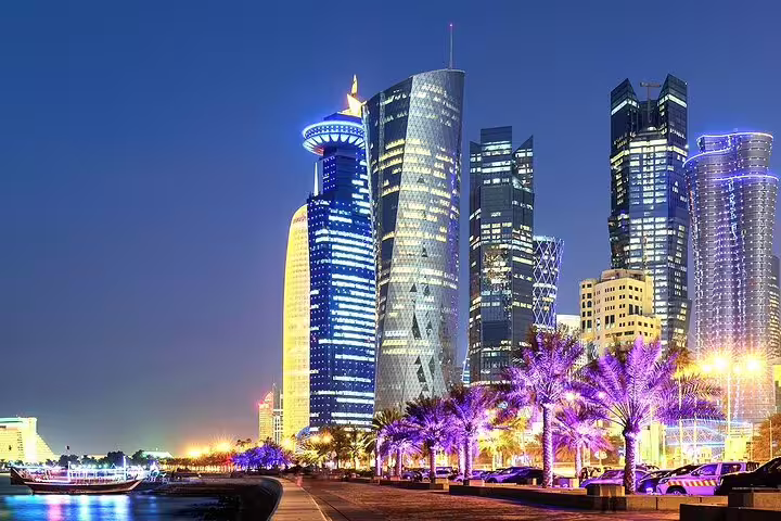Vibrant Doha skyline illuminated at night, showcasing modern skyscrapers during the city tour and dhow boat ride.