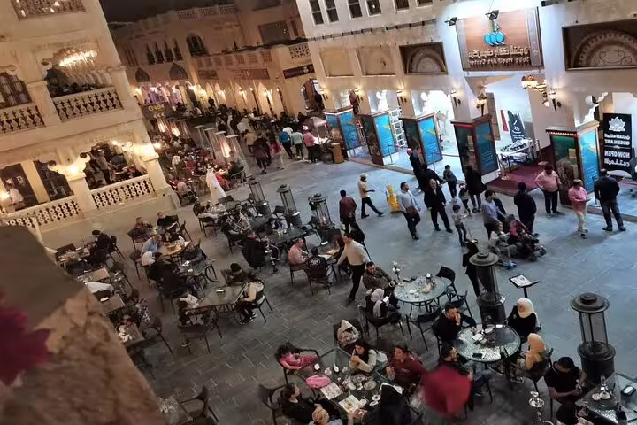 Crowds enjoy dining and socializing at lively Souq Waqif, surrounded by traditional architecture and vibrant evening energy.