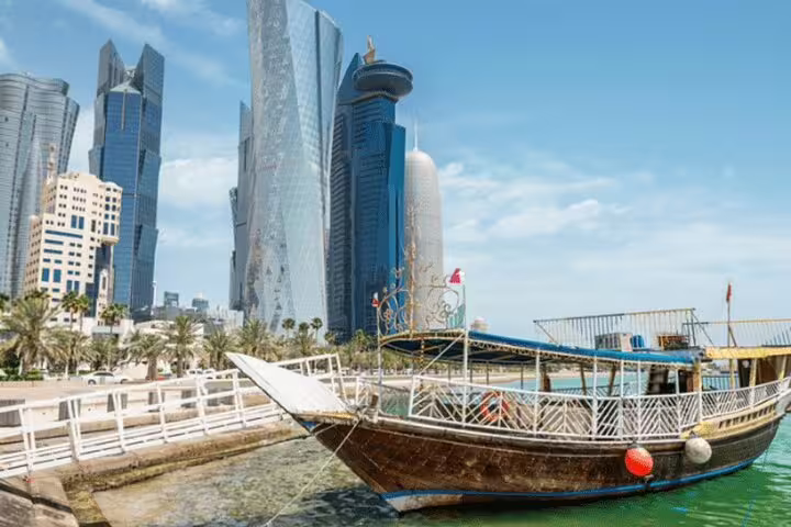Traditional dhow boat docked with Doha's modern skyline in the background, showcasing the blend of culture and architecture.