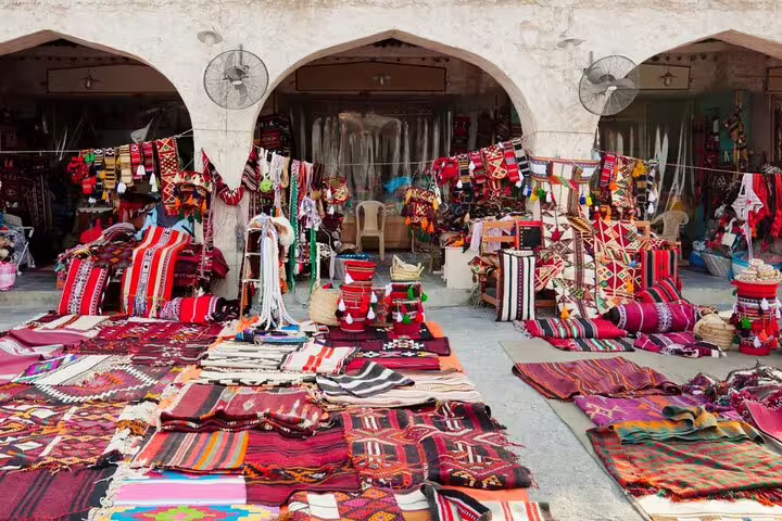 Colorful textiles and rugs displayed in a traditional market in Doha, highlighting local craftsmanship and culture.