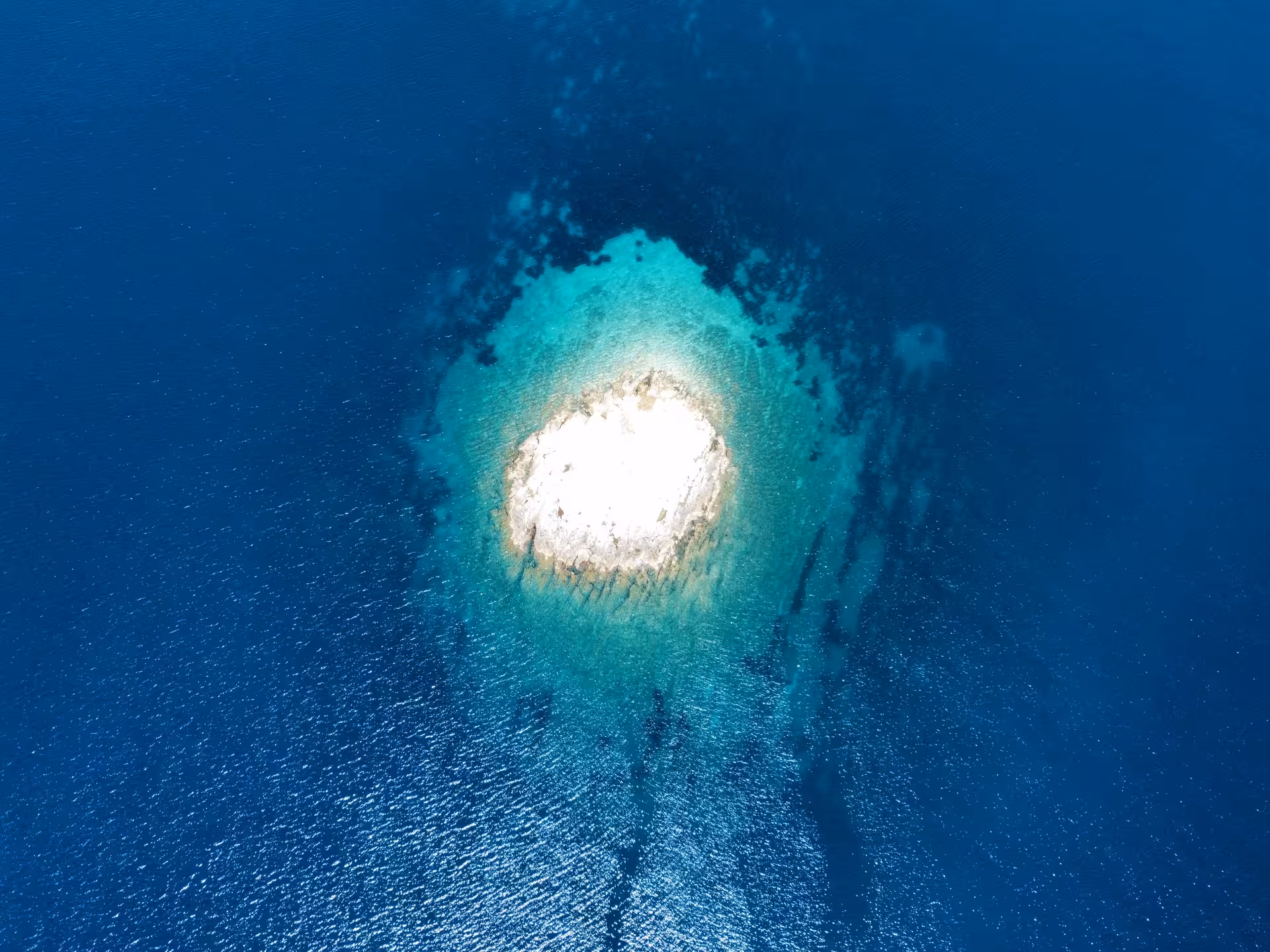 Drone shot of tiny white islet in sapphire Adriatic with bright turquoise shallows, Dolce far niente day trip