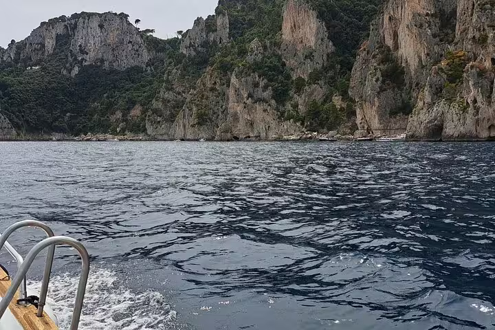Private classic boat tour along Capri cliffs and caves, calm Mediterranean waters on a 4-hour cruise
