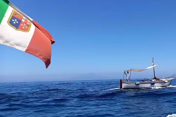 Classic wooden boat cruising off Capri with Italian flag, part of a 4-hour private tour on the Tyrrhenian Sea