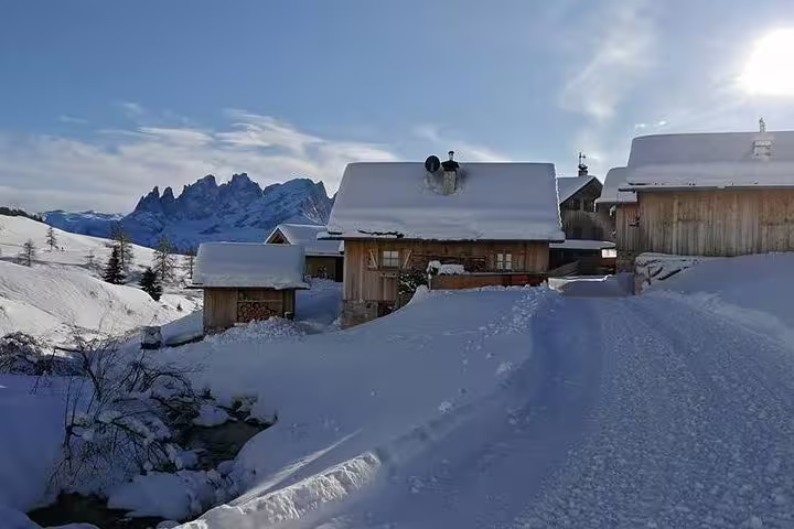 Charming snow-covered alpine village nestled in the Dolomites, ideal for a winter day trip from Venice by luxury car.