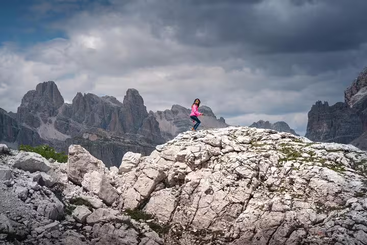 Traveler enjoying panoramic view from rocky peak in the Dolomites on a private day trip from Venice.