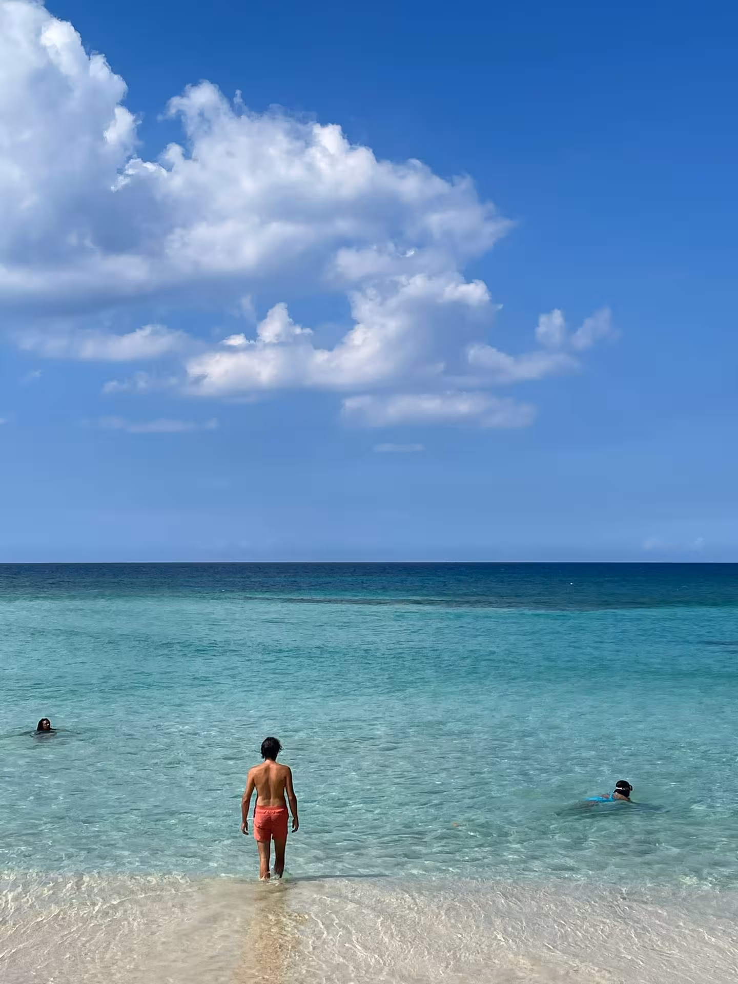 Travelers wading in crystal-clear Caribbean sea under blue sky, Dominican Republic cultural beach day