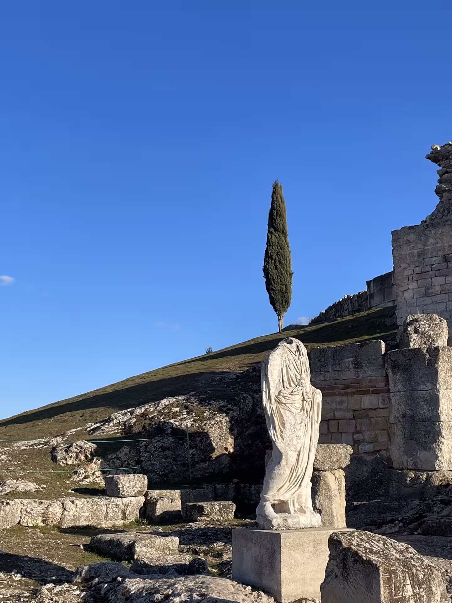 Headless marble statue among Roman ruins under blue sky, scenic stop on the Don Quixote Tour in Spain