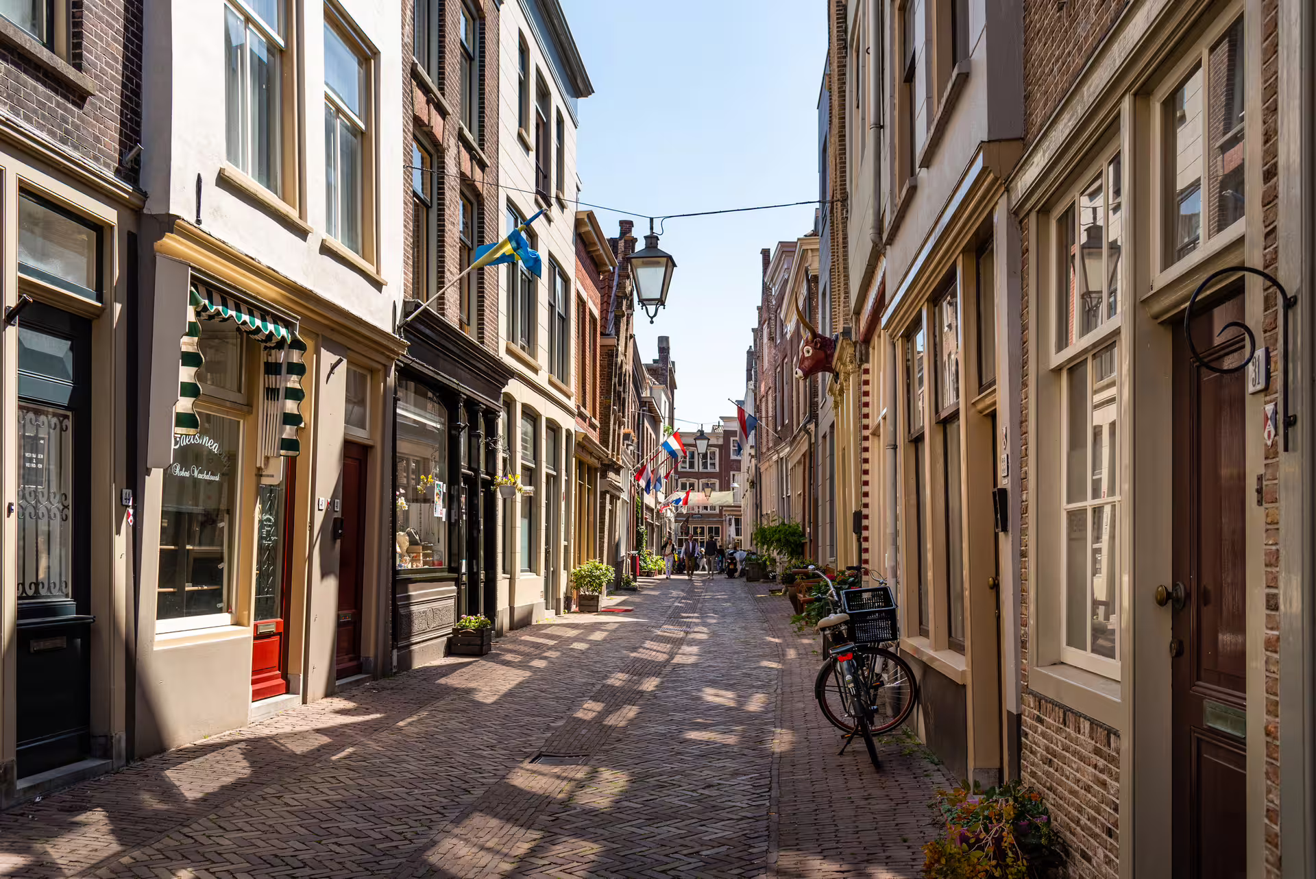 Charming cobbled street in Dordrecht old town with canal houses and bikes, self-guided walking tour audioguide