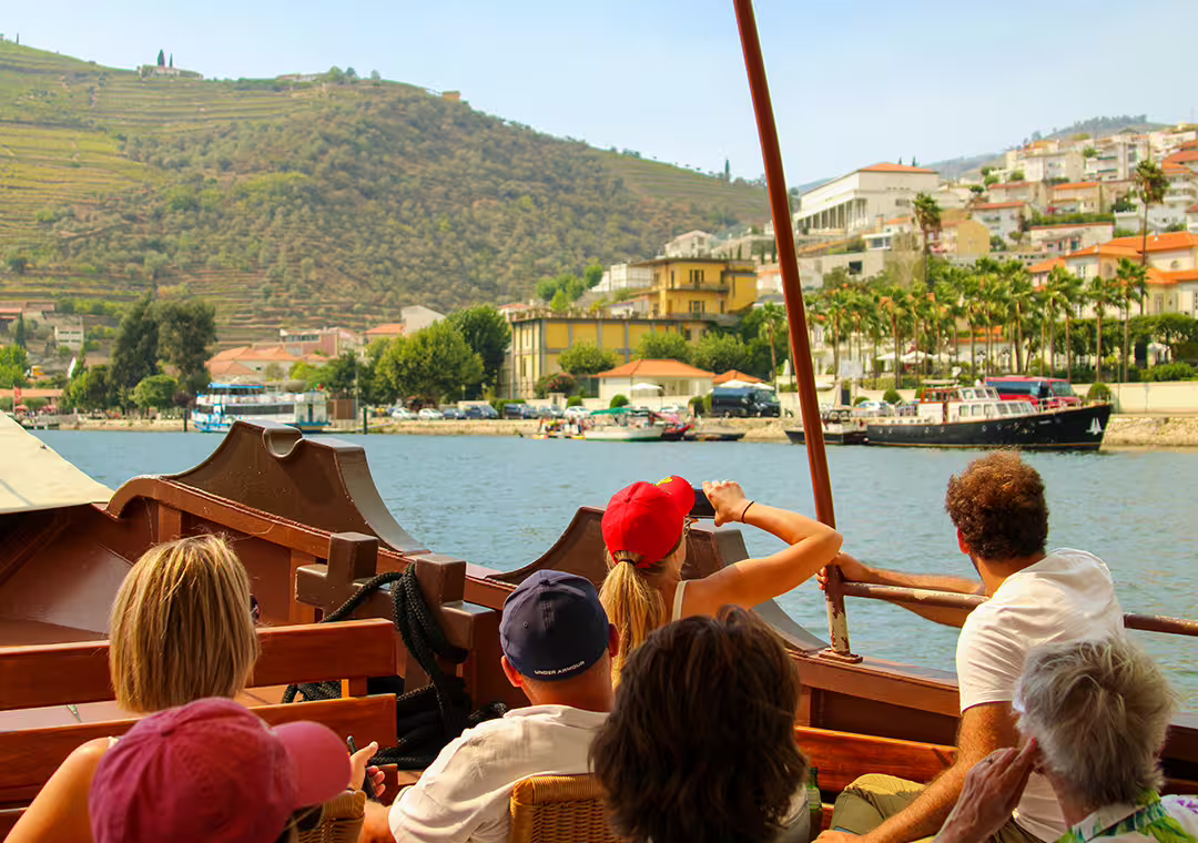 Tourists enjoy a scenic boat ride along the Douro River with views of lush vineyards in the Douro Valley.