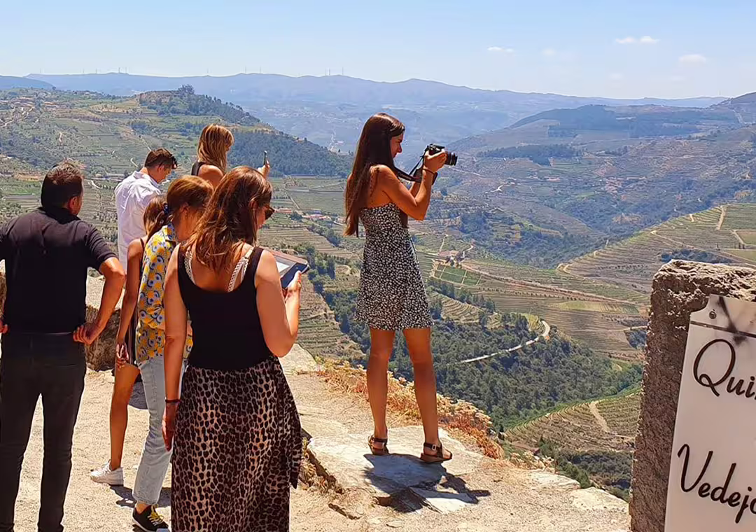Visitors capture stunning panoramic views of the Douro Valley's terraced vineyards and rolling hills.