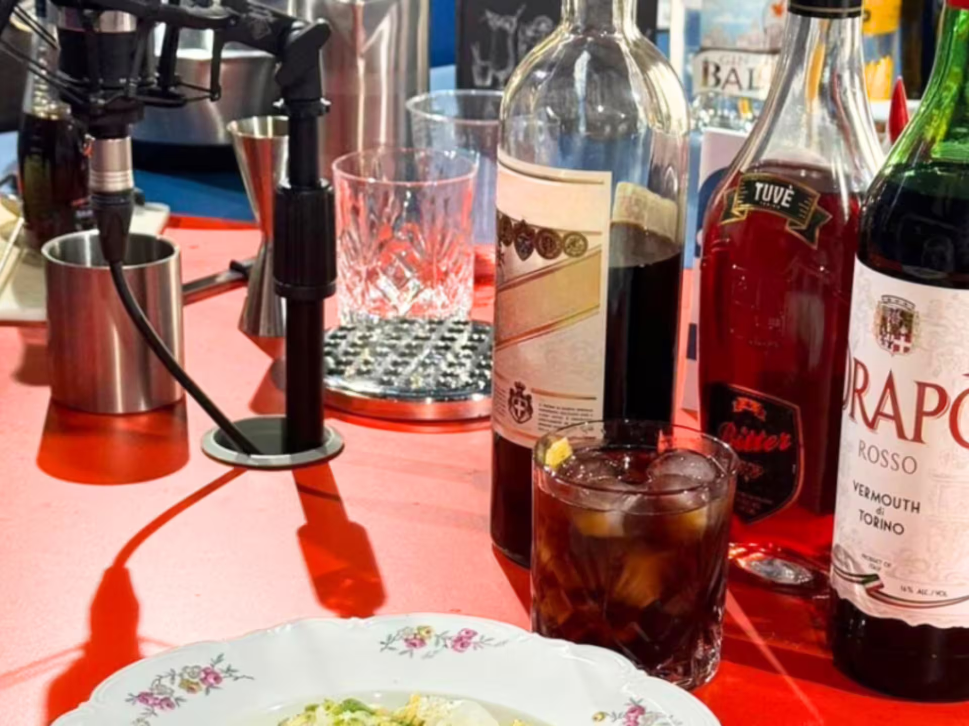 Savor the flavors of Turin with Drapò Rosso Vermouth, drinks, and a gourmet dish at a stylish tasting setup.