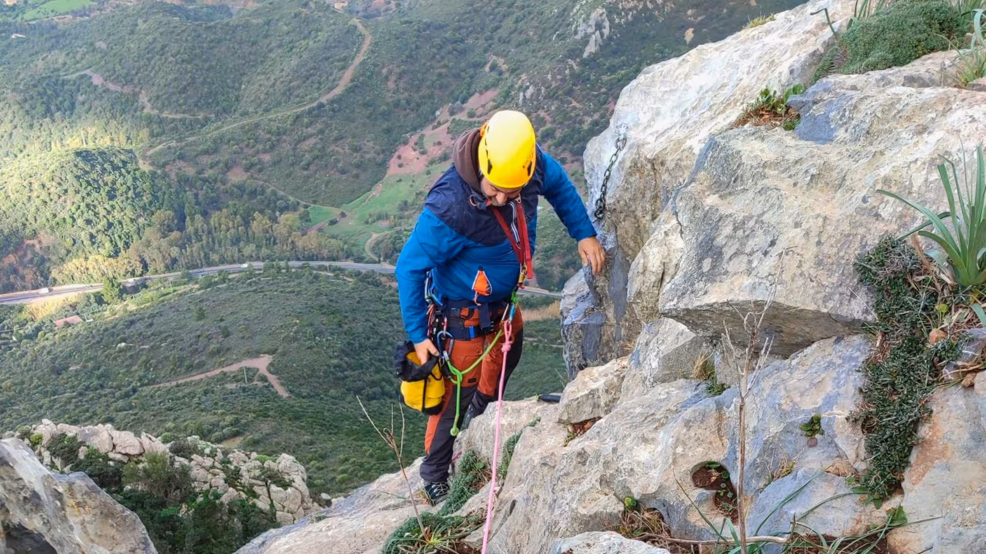 Adventurer in helmet and gear climbing rocky path during dry canyoning on Monte San Giovanni, Gonnesa tour.