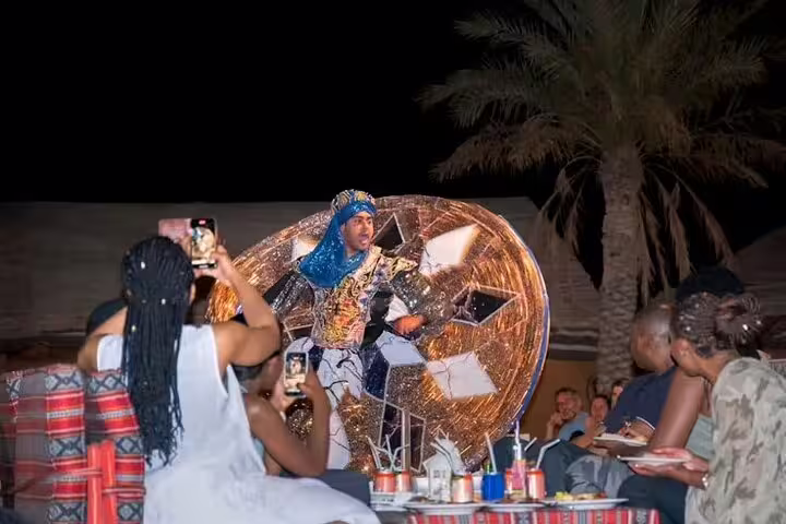 Guests enjoy a colorful tanoura dance performance during a Dubai desert safari BBQ dinner under the night sky