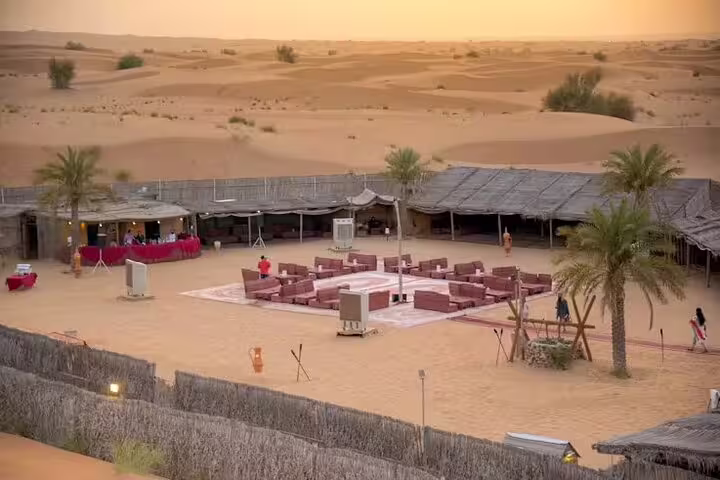 Traditional Bedouin-style desert camp in Dubai at sunset, prepared for BBQ dinner, cultural shows and desert safari guests