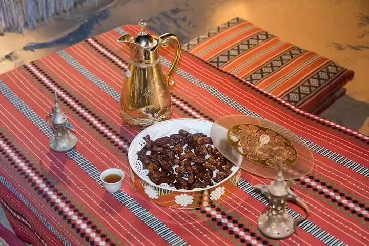 Traditional Arabic coffee pot, dates and sweets on a Bedouin-style table during Dubai desert safari BBQ dinner