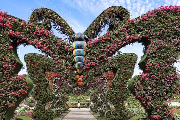 Dubai Miracle Garden pass ticket scene of butterfly flower tunnel archway covered in pink blooms and greenery