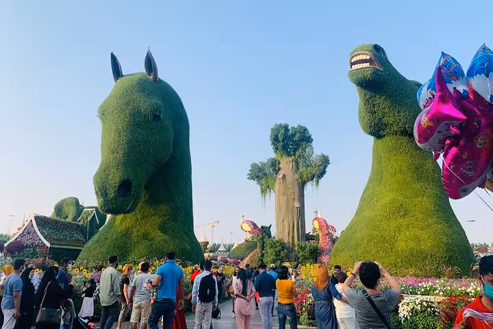 Crowds at Dubai Miracle Garden beside massive green topiary horse and bear, Fujairah transfer included