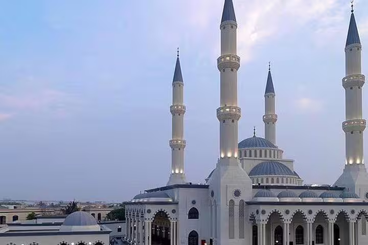 Dubai private half-day tour stop at grand mosque with four minarets and domes at dusk skyline view