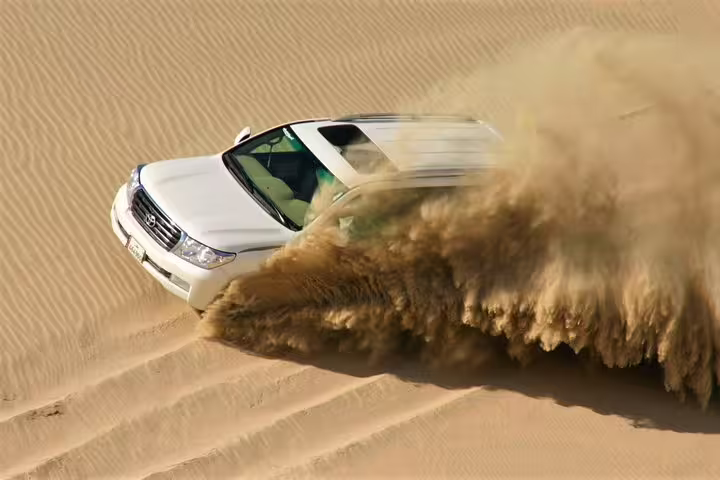 Experience thrilling dune bashing in a 4x4 vehicle navigating through expansive desert sands.